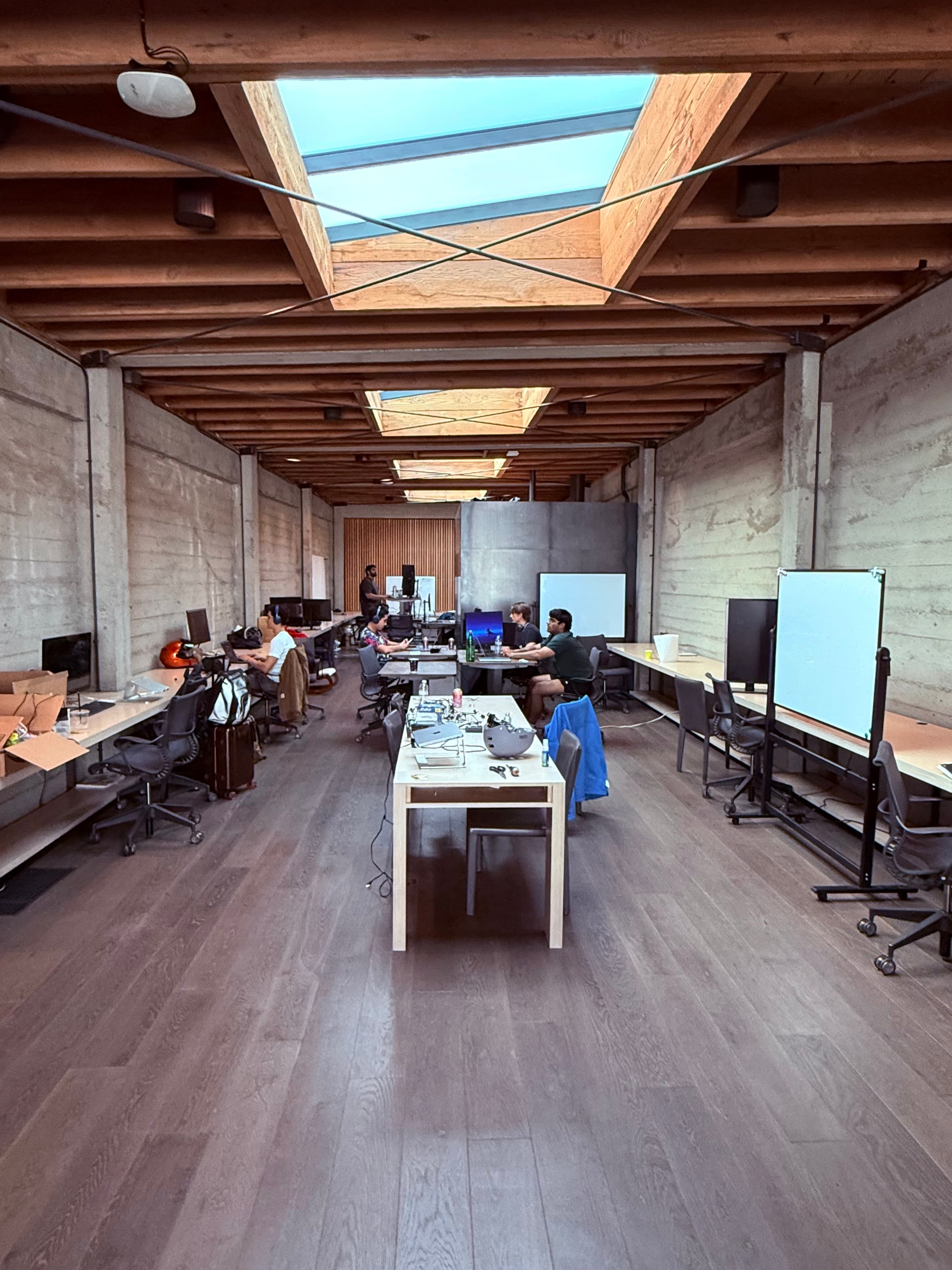 The Anon studio — concrete walls, skylights, and the team heads-down at long shared desks.